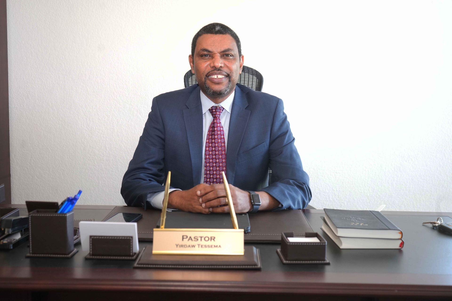 Pastor Yirdaw Tessema seated at his desk